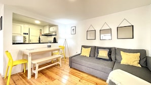 Un salon avec un canapé gris, des coussins jaunes, une table blanche et une chaise jaune.