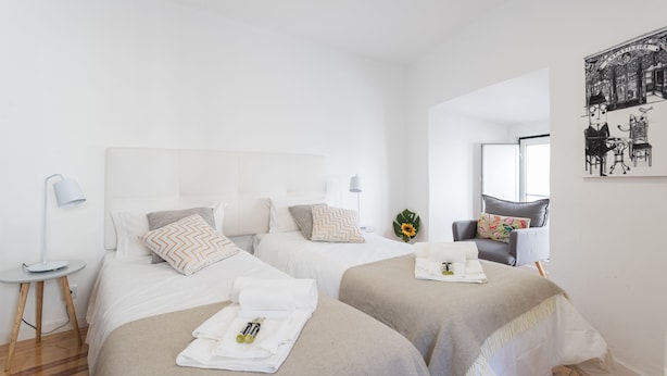 Une chambre d’hôtel avec deux lits, une petite table avec une lampe, une chaise et une œuvre d’art accrochée au mur.