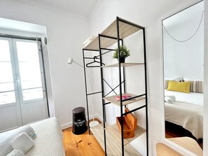Una habitación de hotel moderna con una cama, un escritorio pequeño, un cesto de basura negro y un espejo.