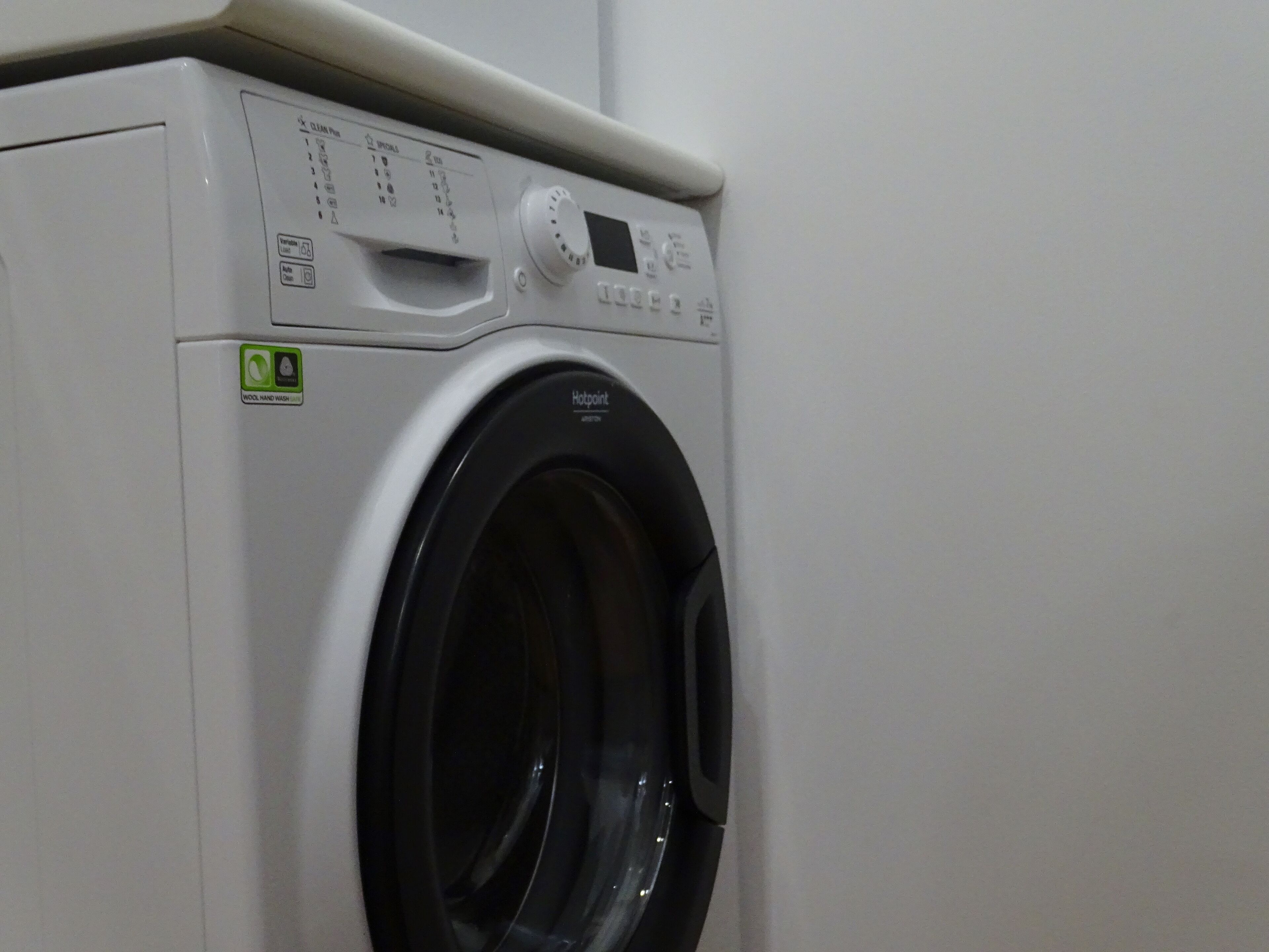 Vue de face d’un lave-linge moderne à chargement frontal, de couleur blanche, doté d’un écran numérique et d’un panneau de commande.