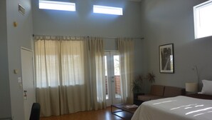 Een slaapkamer met een bed, een bank, een bijzettafeltje, een stoel en een deur naar een balkon.