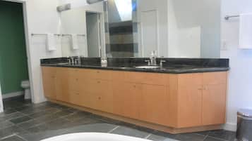 Un baño con un tocador amplio, una bañera y un espejo.
