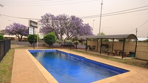 A rectangular swimming pool with a tiled edge, surrounded by a paved area. - Aromet Motor Inn (Temora)