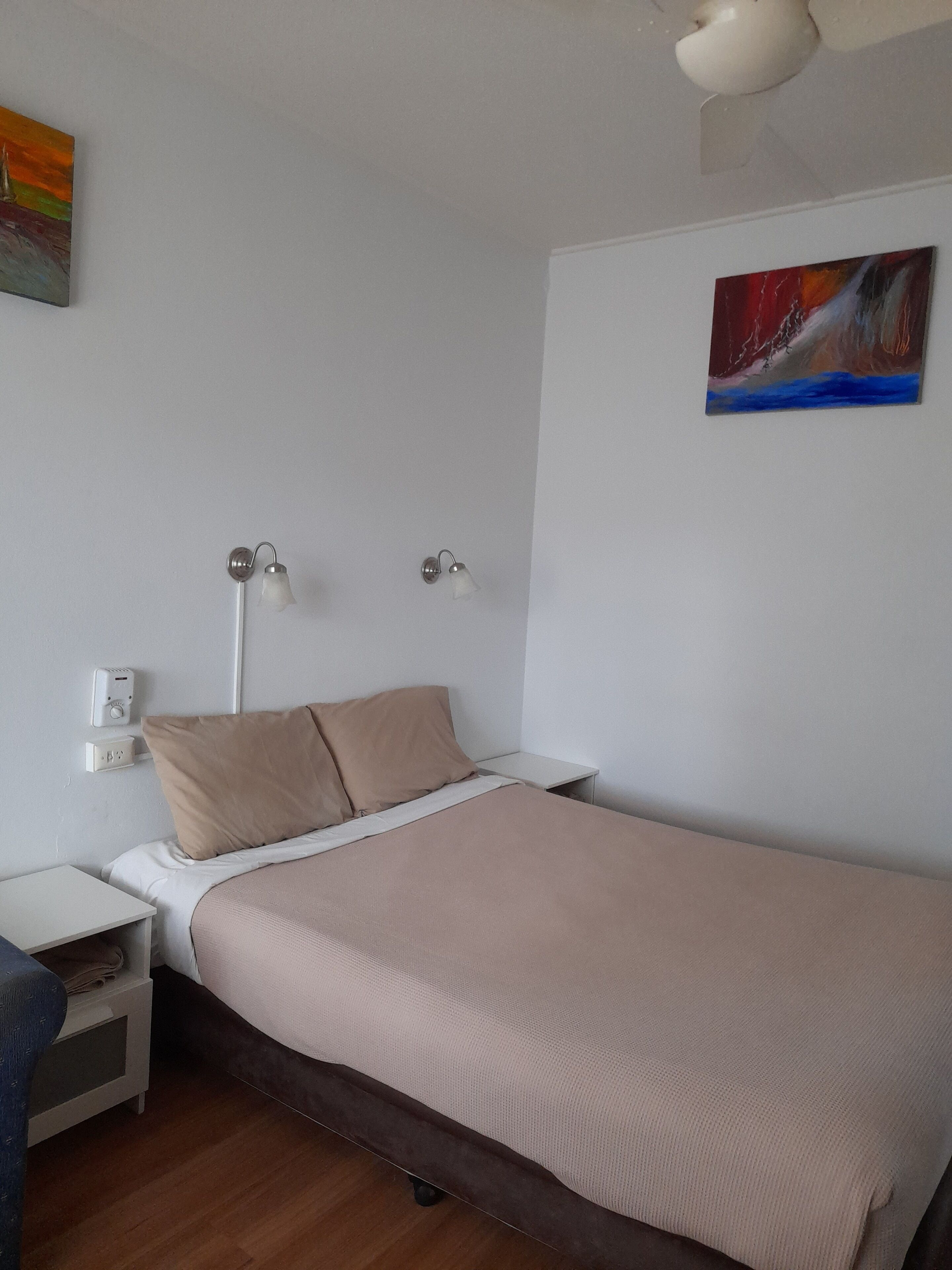 A bedroom with a bed, bedside tables, a lamp, and a painting on the wall.