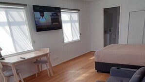 A modern room with a grey sofa, a wooden desk, and a bed. - Aromet Motor Inn (Temora)