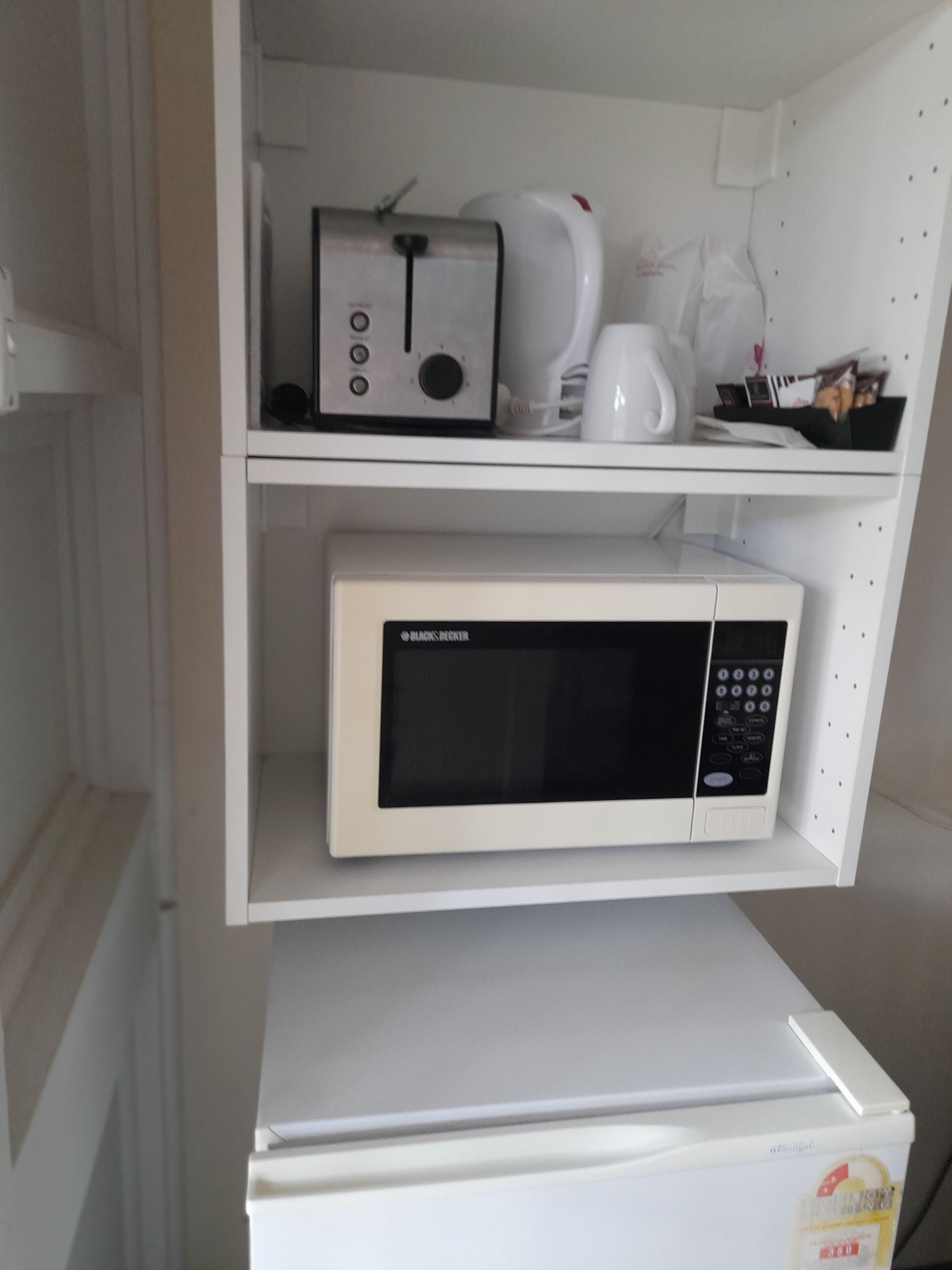 Una cocina con microondas, tostadora y cafetera sobre la encimera.