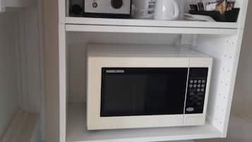 Una cocina con microondas, tostadora y cafetera sobre la encimera.