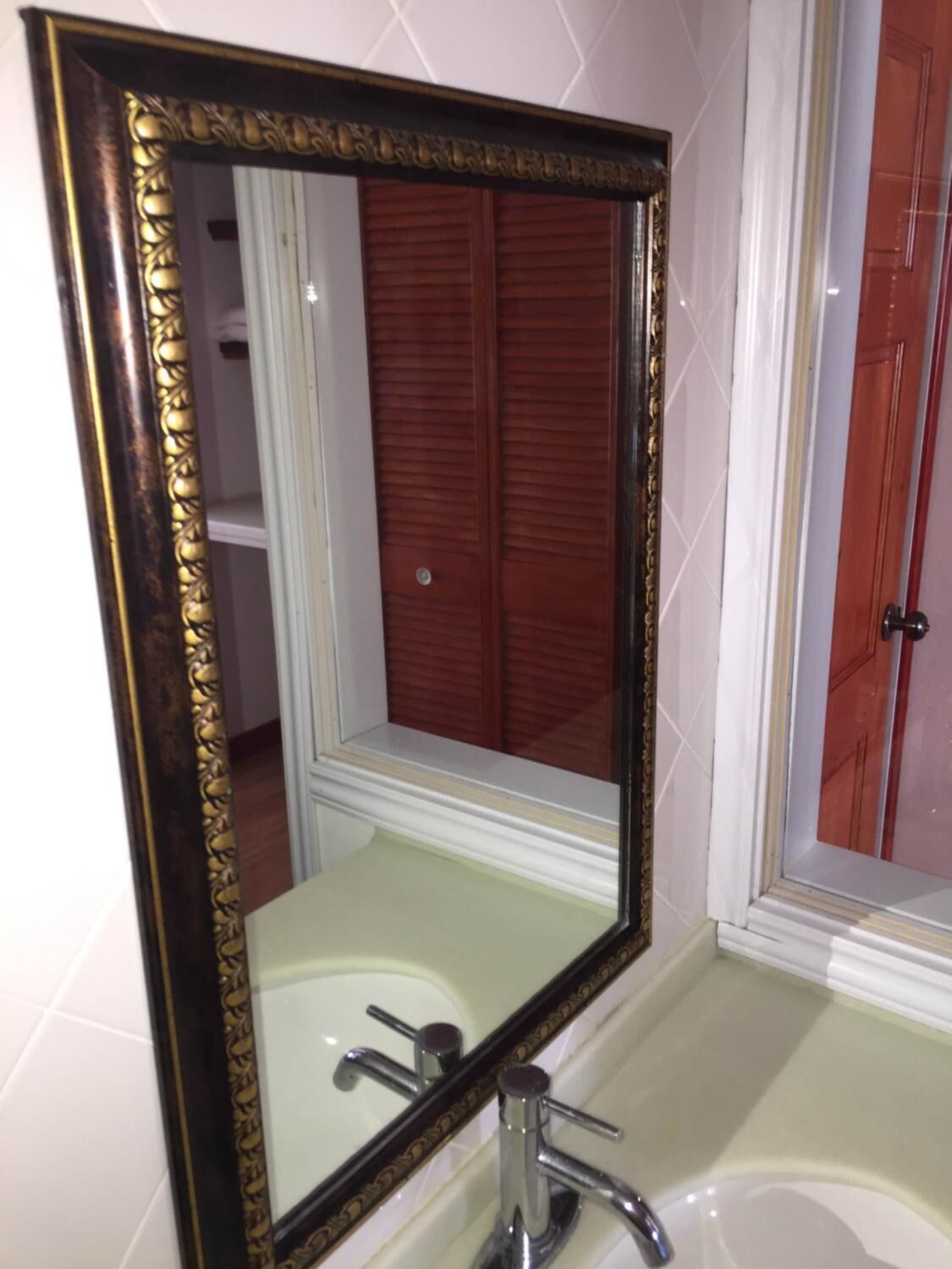 A bathroom with a large mirror, a sink, and a door with a wooden panel.