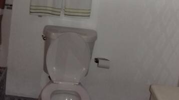 A bathroom with a toilet, a shower curtain, and a towel rack.