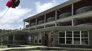 A two-story building with a stone facade, multiple balconies, and large windows. - Spring Gardens Resort (Biabou)