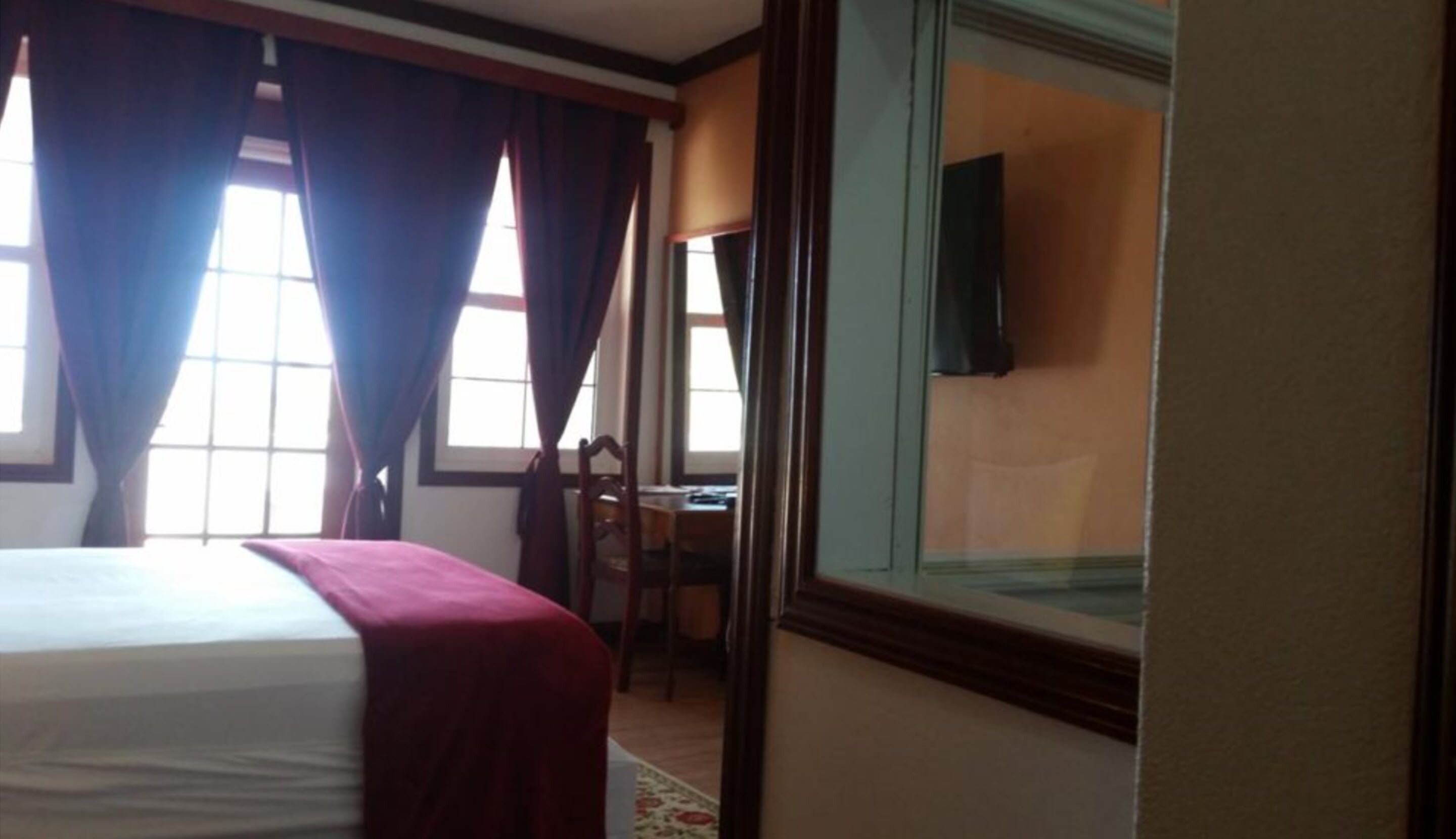 A hotel room with a bed, a desk, and a television on the wall.