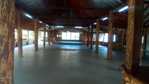 A spacious indoor area with a high ceiling and wooden beams, featuring a central open space and multiple windows. - Spring Gardens Resort (Biabou)