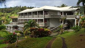 A two-story building with a stone facade, multiple balconies, and a pathway leading to the entrance. - Spring Gardens Resort (Biabou)