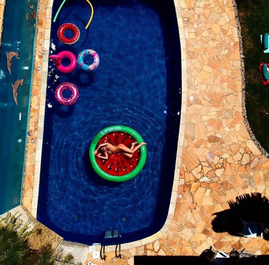Ein Schwimmbecken mit einer Person, die auf einer Schwimmplattform liegt, umgeben von bunten Schwimmringen.