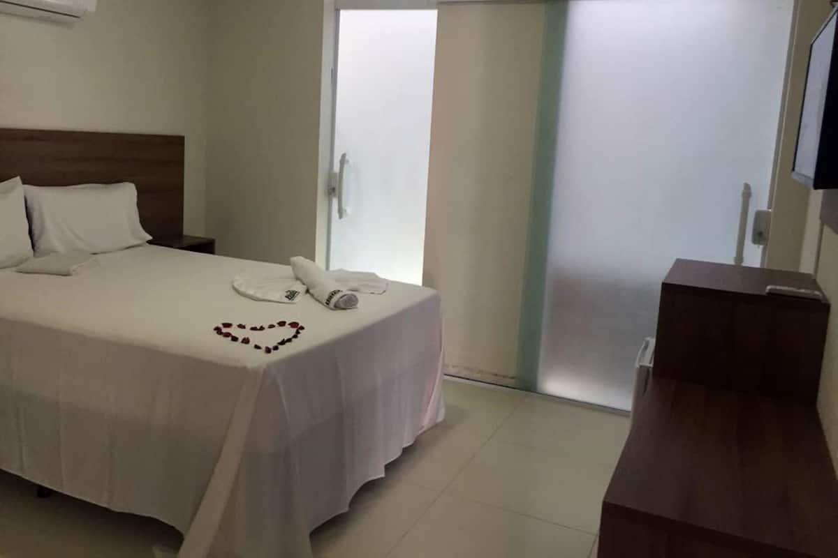 A hotel room with a bed, a bedside table, a desk, and a sliding door.
