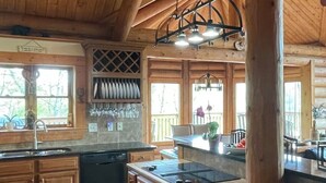 Une cuisine spacieuse avec des meubles en bois, un grand îlot central et un plafond haut avec des poutres apparentes.