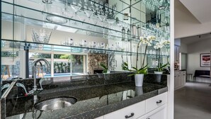 Eine Küche mit schwarzer Granitabdeckung, weißen Schränken, einer Edelstahlspüle und einer großen Glasrückwand.