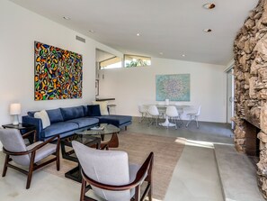 A modern living room with a sectional sofa, a glass coffee table, and a dining area with a round table and chairs.