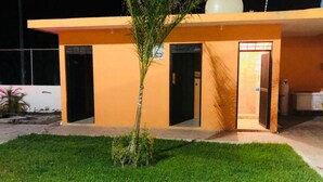 Ein Gebäude mit flachem Dach, zwei Türen und einem kleinen Baum im Vorgarten.