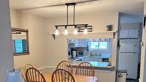 Ein Essbereich mit Holztisch und -stühlen, einer Lampe und einer Küche im Hintergrund.