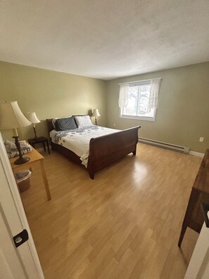 A bedroom with a bed, two bedside tables, a window, and a radiator. - A Great Vacation Getaway!! (North Woodstock)