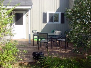 A patio with a table and chairs, a dog, and a house in the background. - A Great Vacation Getaway!! (North Woodstock)