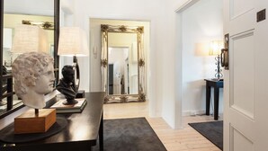 A room with a wooden desk, a bust sculpture, a large mirror, and a door leading to another room.