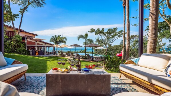 Un espacio exterior lujoso con vistas al océano, una piscina y un bar.