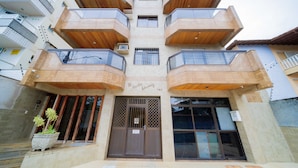 A multi-story building with a central entrance, balconies, and a potted plant outside.