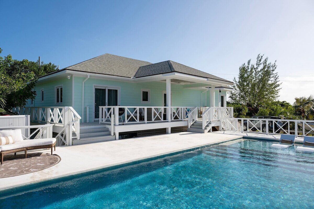 A house with a pool, white railings, and a covered patio area.