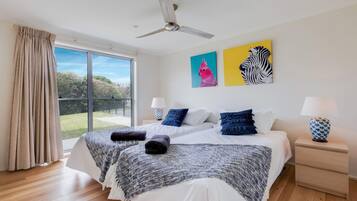 Une chambre avec un grand lit, deux tables de chevet, un ventilateur de plafond et des œuvres d’art accrochées au mur.