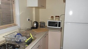 Pieni, käytännöllinen keittiönurkkaus, jossa on pesuallas, vedenkeitin, leivänpaahdin, mikroaaltouuni ja jääkaappi.