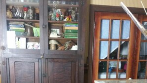 Un comedor con una mesa redonda, sillas de madera y un armario con puertas de cristal.