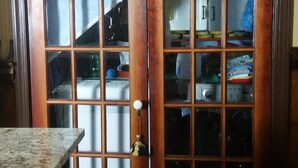Una puerta de madera con paneles de vidrio que da a una habitación donde se ve un área de cocina.