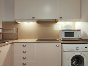 A kitchen with a microwave, a washing machine, and a sink.