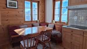 Een gezellig houten cabin interieur met een eettafel, stoelen, een bank en een keuken met een fornuis.
