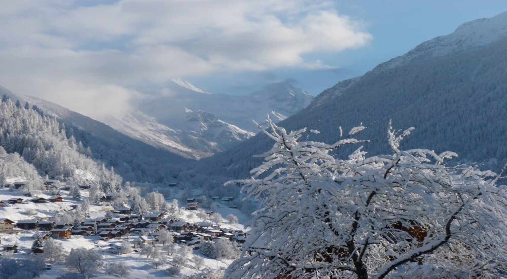 Een berglandschap bedekt met sneeuw, met een dorp in de vallei.