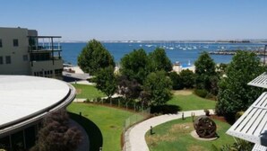 A view of a coastal area with a building, a grassy area, and a body of water with boats.