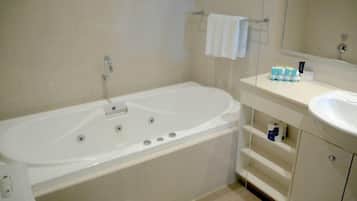A bathroom with a white bathtub, a sink, and a mirror.