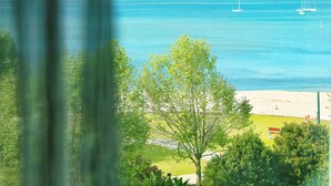 A coastal view with a sandy beach, a grassy area, and a few boats on the water.