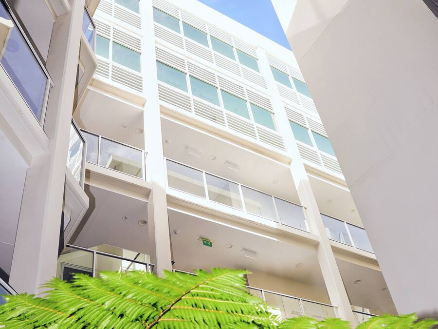 Ein mehrstöckiges Gebäude mit modernem architektonischen Design, das Balkone und große Fenster aufweist.