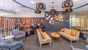 A modern lobby with a seating area, a reception desk, and a decorative wall with leaf patterns.