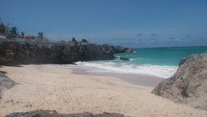 Una playa con aguas turquesas cristalinas, una orilla arenosa y acantilados rocosos.