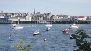 A harbor with multiple sailboats and a town in the background. - Shiantview Cottage - Magnificent Sea Views  (Stornoway, Isle of Lewis, Scotland)
