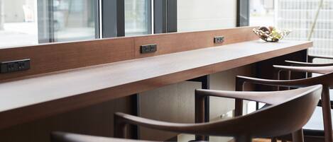 A long wooden table with built-in electrical outlets, surrounded by wooden chairs.