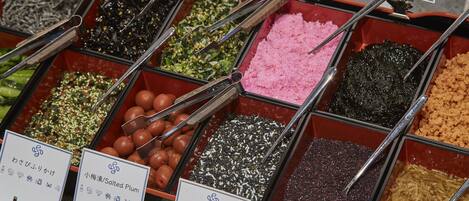 A variety of food items in containers with tongs, each labeled with Japanese text.