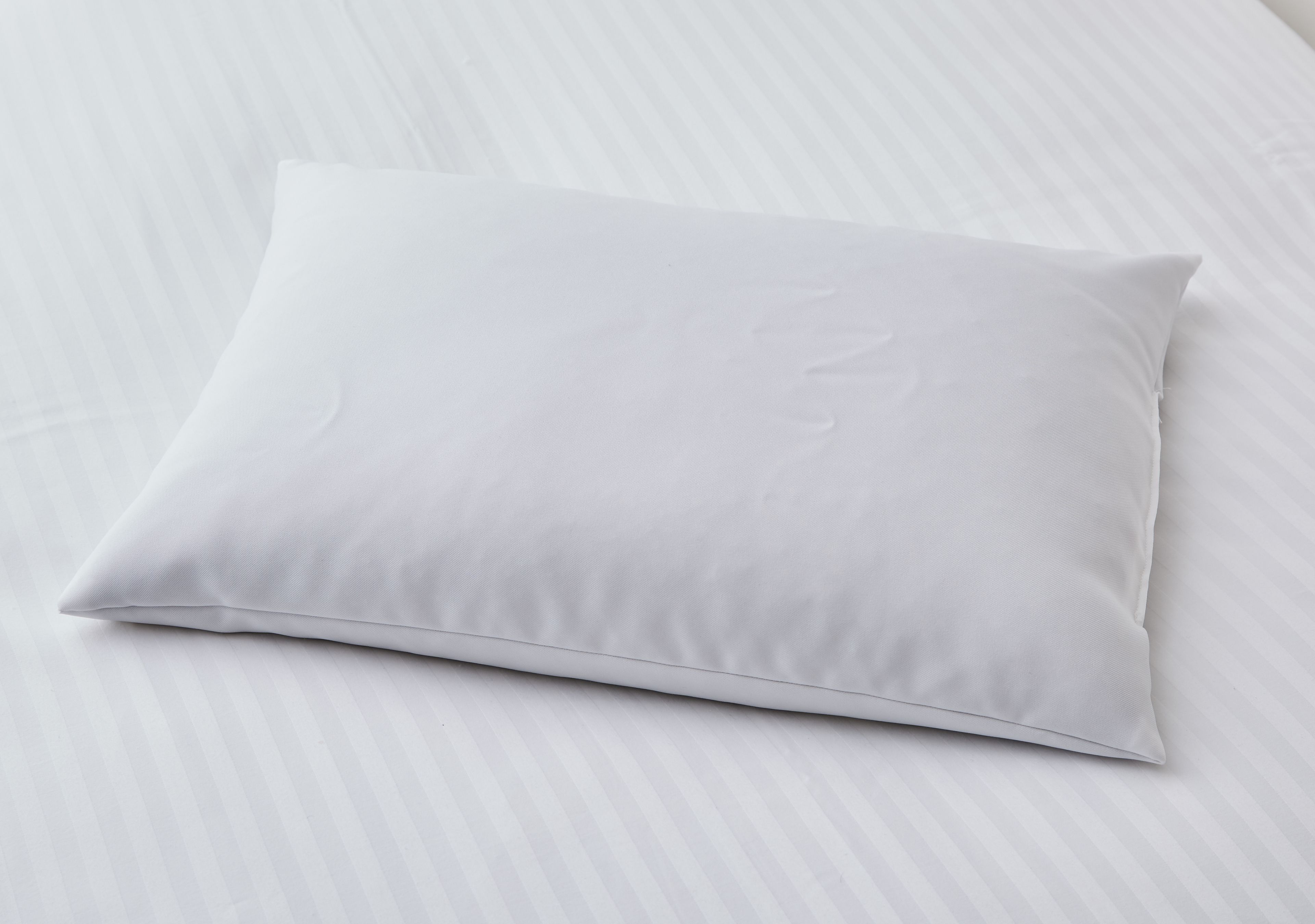 A white pillow on a bed with a striped pattern.