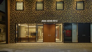 The exterior of Iroha Grand Hotel with a patterned facade, large glass doors, and a visible interior with seating and tables. - Iroha Grand Hotel (Matsumoto)