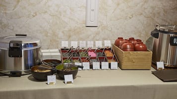 Montaje de bufé con varios recipientes de comida y una olla arrocera.