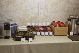 Montaje de bufé con varios recipientes de comida y una olla arrocera.